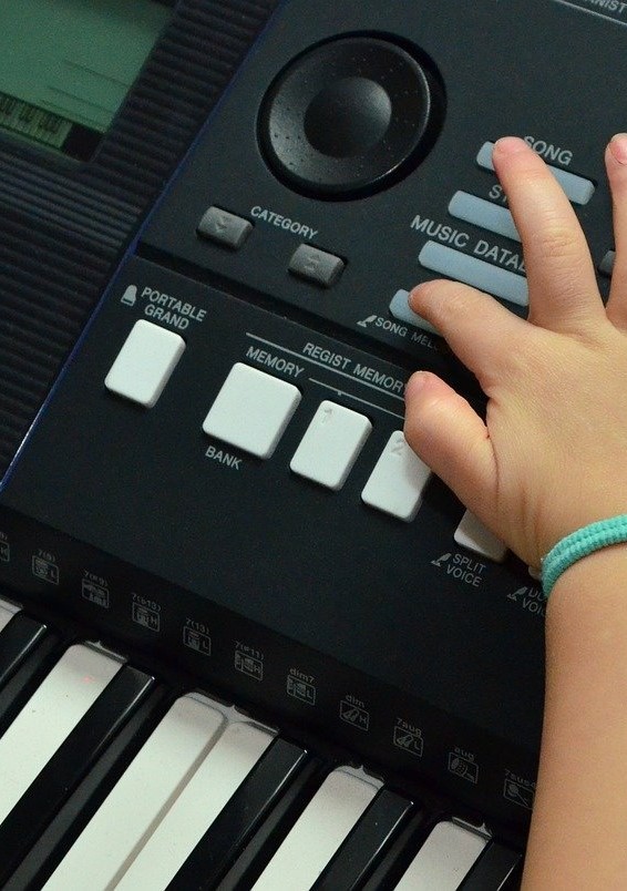 Eine Kinderhand drückt Tasten auf einem Keyboard